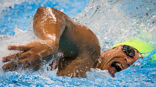 Nadador se exercita na piscina, demonstrando muito esforço nas contrações do rosto