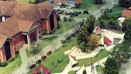Imagem aérea do campus mostra praça e telhados da biblioteca