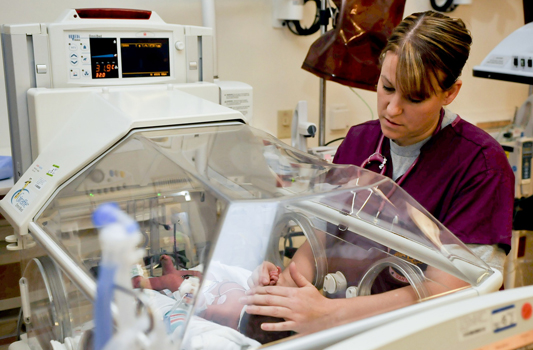 Enfermeira cuidando de bebê na incubadora