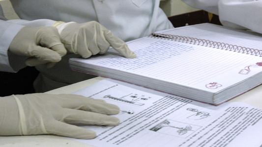 Fotos das mãos com luvas de médico apontando para caderno e papéis de estudo