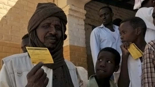 Moradores da região de Darfur com cartão de vacinação em mãos