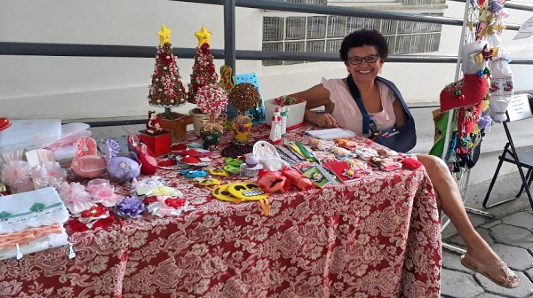 Mulher sentada vendendo artesanatos da feira