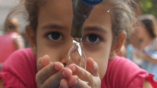 Imagem de menina bebendo água em fonte