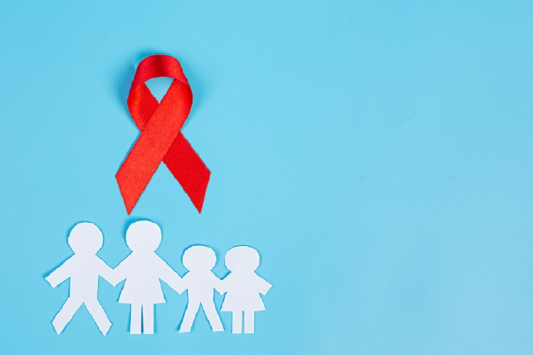 Laço vermelho, símbolo da luta contra Aids, em cima de um desenho com pai, mãe e um casal de filhos pequenos