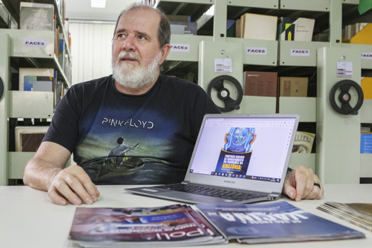 Julio Cesar mostrando a capa do livro na tela de um computador