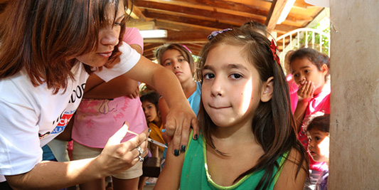Mulher aplicando vacina em uma criança
