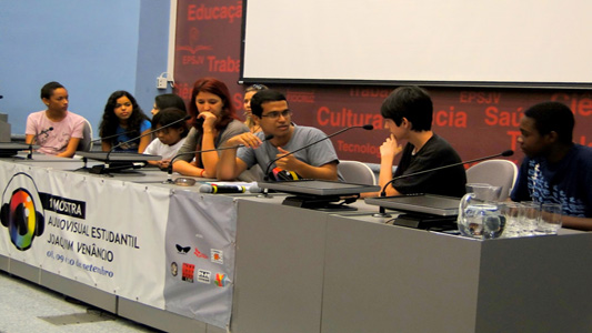 Nove estudantes sentados à mesa de apresentação da primeira mostra realizada pela Escola Politécnica de Saúde Joaquim Venâncio