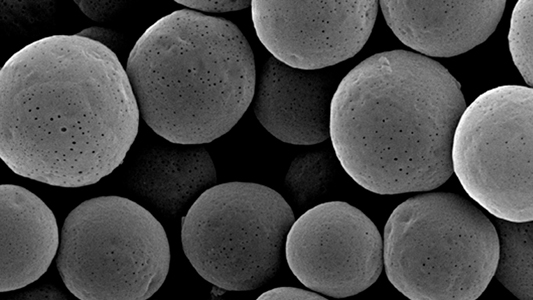 microesferas de poliestireno ampliadas por microscópio (parecem pequenas bolas irregulares)