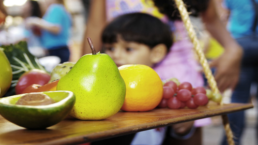 Criança ao fundo de uma mesa com frutas frescas