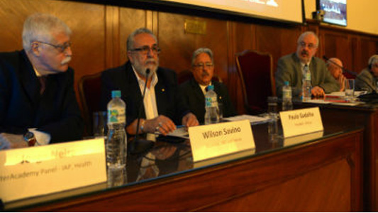 Foto da mesa de abertura com Jorge Neira, da IAP for Health (em primeiro plano); Wilson Savino, diretor do IOC; Paulo Gadelha, presidente da Fiocruz; e Marcello Barcinscki, da ANM