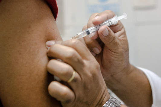 Mulher tomando vacina no braço