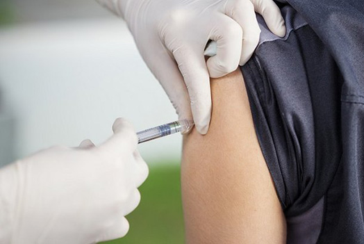 Foto de aplicação de vacina no braço por profissional de saúde