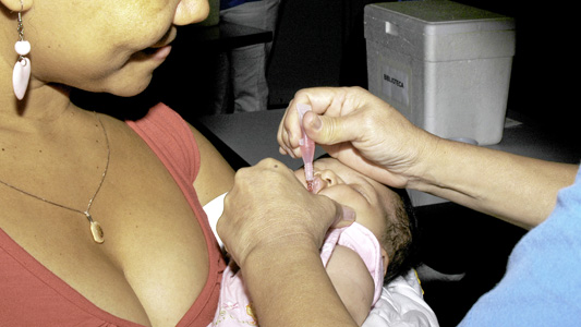 Foto de mãe com bebê no colo tomando vacina