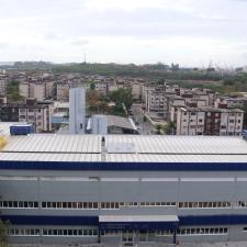 Foto da fachada do Centro de Pesquisa, vista do alto. É um prédio cinza, com duas listras azuis, uma próximo ao teto e outra na altura do segundo pavimento. Na frente, há o nome completo do Centro e os logos da Ensp e do IOC. Ao fundo, vê-se parte do conjunto de favelas da Maré e da baía de Guanabara