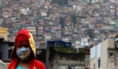 Menino de máscara na entrada de uma favela