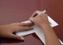 Mãos de adolescente escrevendo num caderno
