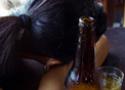 Foto de uma mulher dormindo em uma mesa com uma garrafa de cerveja do lado