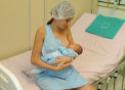 Mulher amamentando bebê em maca de hospital
