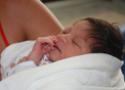 Detalhe de braço de mulher segurando um recém nascido dormindo