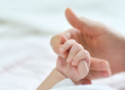 Mão de um bebê segurando o dedo da mãe