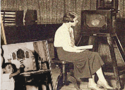 Foto antiga, em sépia, de uma mulher de perfil sentada em uma sala