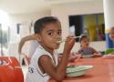 Criança comendo no refeitório da escola