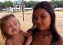 Menina com bebê no colo em aldeia indígena