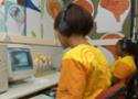 Adolescentes operam computador, com fones de ouvido
