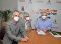 executivos reunidos em torno de mesa de trabalho, usando máscaras de proteção contra Covid-19