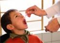Menino tomando vacina em gotas