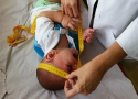 Pediatra medindo a cabeça de um bebê