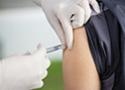 Foto de mãos profissional de saúde usando luvas e aplicando vacina no braço de uma pessoa
